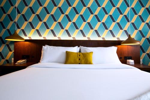 a bedroom with a large bed with a yellow pillow at Unscripted Durham, Part of JDV by Hyatt in Durham