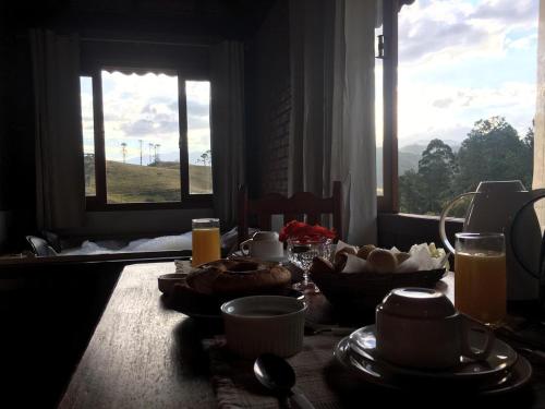 a table with food and a window with a view at Pousada Chales Joao de Barro in Visconde De Maua
