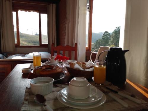 a dining room table with breakfast food and a window at Pousada Chales Joao de Barro in Visconde De Maua
