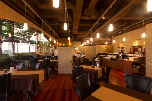 un restaurante con mesas y sillas y un bar en Ohta Grand Hotel en Ota