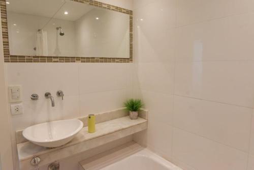 uma casa de banho branca com um lavatório e um espelho em Departamento Playa 3 em Mar del Plata