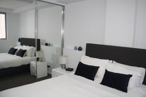 1 dormitorio con 2 camas y almohadas blancas y negras en North Sydney Wyndel Apartments-MIL1005, en Sídney