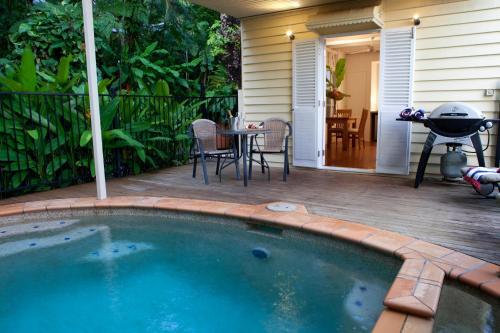 a swimming pool on a patio with a table and a grill at Port Douglas Cottage & Lodge in Port Douglas