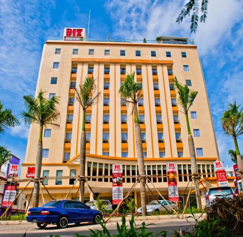 a building with palm trees in front of it at Biz Hotel Batam in Nagoya