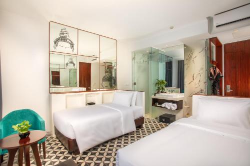 a hotel room with two beds and a table at UTEY Hotel in Siem Reap