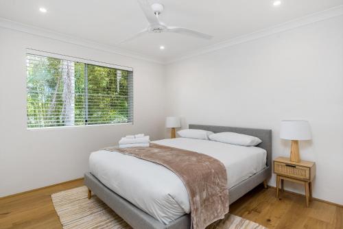 een witte slaapkamer met een bed en een raam bij Roses Byron in Byron Bay