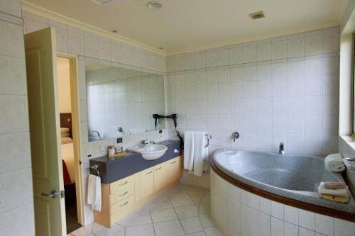 a bathroom with a tub and a sink at Regal Palms Resort in Rotorua