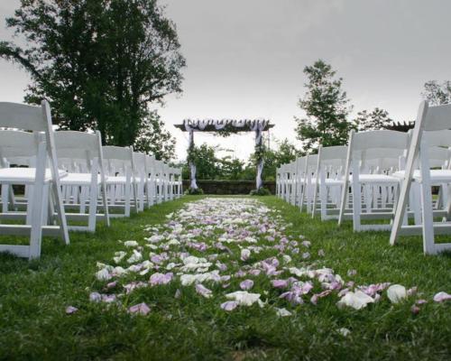a aisle with white chairs and flowers in the grass at Nantahala Village in Bryson City