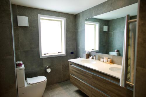 a bathroom with a sink and a toilet and a mirror at Regal Palms Resort in Rotorua