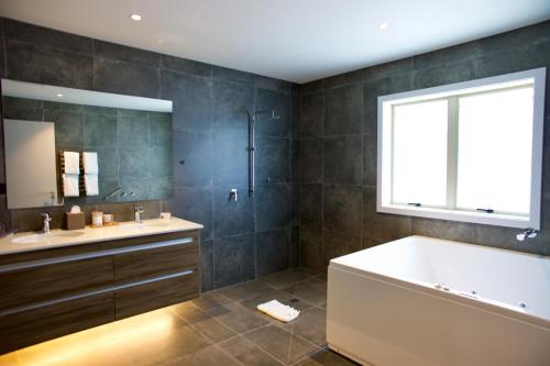 a bathroom with a tub, sink, mirror and bathtub at Regal Palms Resort in Rotorua