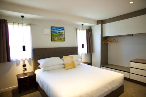 a bedroom with a large white bed and two windows at Regal Palms Resort in Rotorua