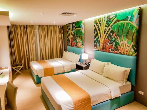 プエルト・プリンセサにあるアジザ パラダイス ホテルのベッド2台が備わる客室で、壁には絵画が飾られています。