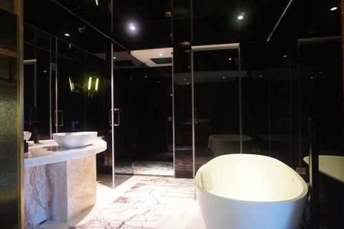 a bathroom with a tub, sink, and mirror at The Macau Roosevelt Hotel in Macau