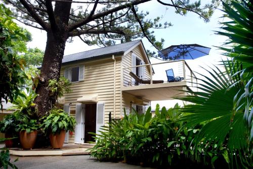 a house with a balcony with a blue umbrella at Port Douglas Cottage & Lodge in Port Douglas