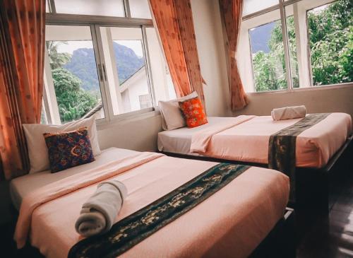two beds in a room with two windows at Thaweesuk Heritage Homestay in Phangnga