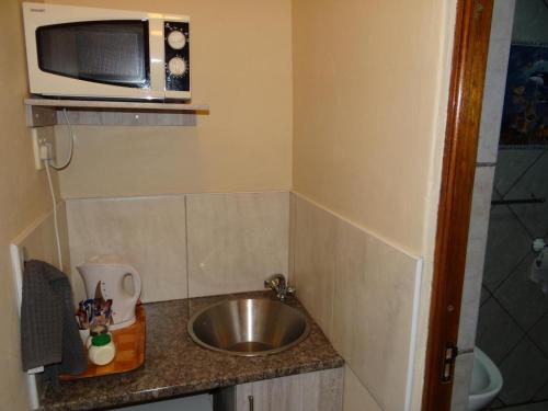 a small kitchen with a sink and a microwave at Lephalale Guest House in Ellisras