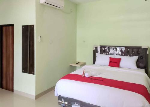 una camera da letto con un grande letto bianco con cuscini rossi di RedDoorz near Taman Wisata Alam Punti Kayu Palembang 2 a Sukarami
