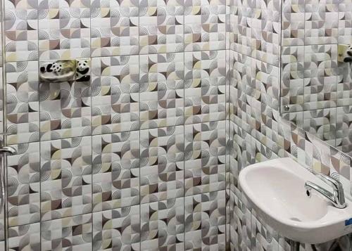 bagno con lavandino e doccia con pareti piastrellate di RedDoorz near Taman Wisata Alam Punti Kayu Palembang 2 a Sukarami