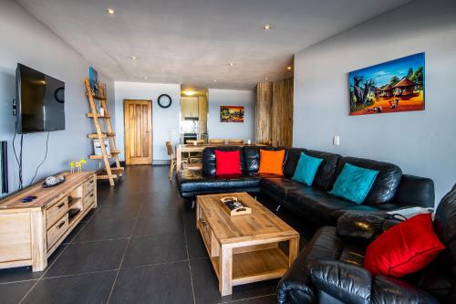 a living room with a black leather couch and a table at Lazy Lizard 23 in Umdloti