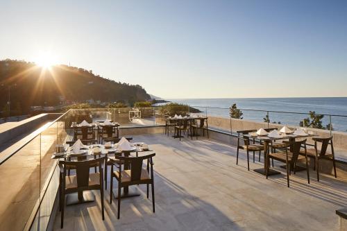 a restaurant with tables and chairs on a balcony with the ocean at Ricosta Hotel in Rize