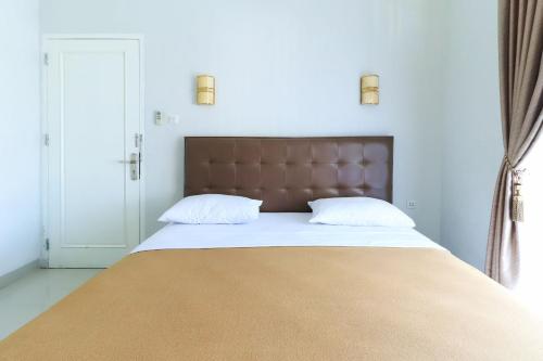 a large bed with a brown headboard and two pillows at Ge JacMart Homestay Makassar in Makassar