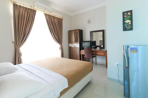 a bedroom with a bed and a desk and a window at Ge JacMart Homestay Makassar in Makassar
