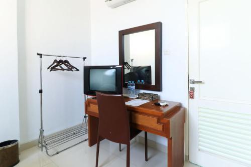 a desk with a television and a mirror in a room at Ge JacMart Homestay Makassar in Makassar