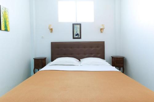 a bedroom with a large bed with a orange blanket at Ge JacMart Homestay Makassar in Makassar
