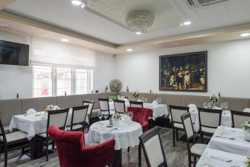 a dining room with tables and chairs and a painting at Hotel Alibi Sabac in Šabac