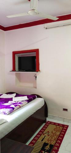a room with two beds and a tv on the wall at Om Datta Krupa Niwas Cottage in Mahabaleshwar