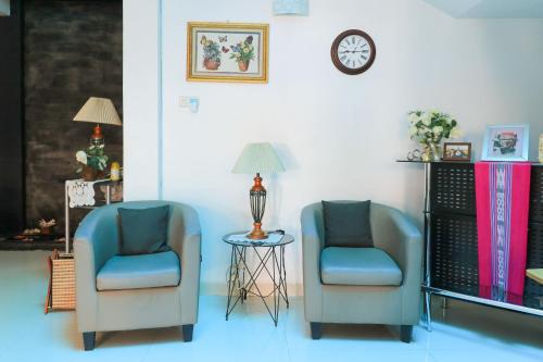 two chairs and a table with a clock on a wall at Ge JacMart Homestay Makassar in Makassar