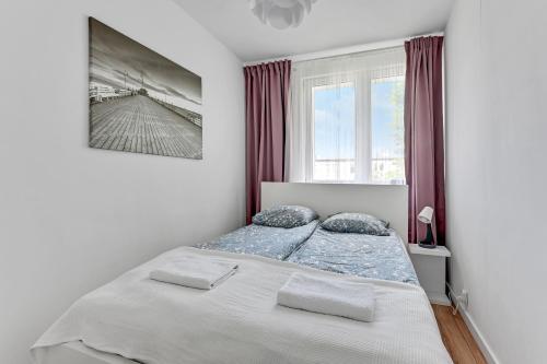 グダニスクにあるApartament Nadmorskiの白いベッドルーム(ベッド1台、窓付)
