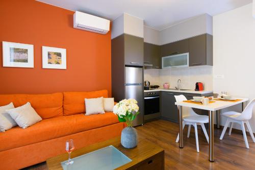a living room with an orange couch and a kitchen at Elounda Colour Apartments in Elounda