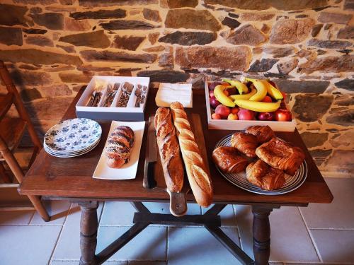 einen Tisch mit verschiedenen Brotsorten und Früchten in der Unterkunft LE DOMAINE DE COAT ROGAN, La chambre du Jaudy in Pommerit-Jaudy