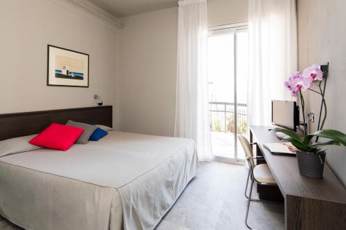 a bedroom with a bed and a desk and a window at Hotel Tirreno in Spotorno
