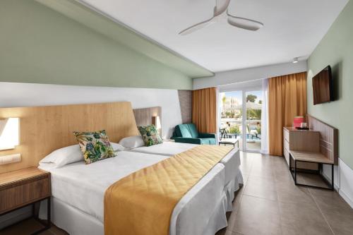 プラヤ・デ・パルマにあるHotel Riu Playa Park - 0'0 All Inclusiveの大きなベッドとバルコニーが備わるホテルルームです。