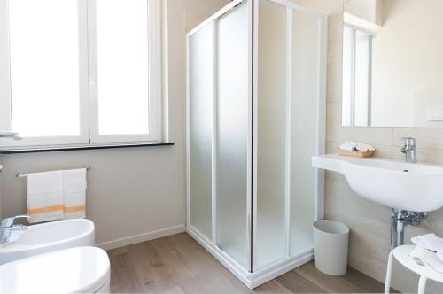 a white bathroom with a sink and a toilet at Hotel Tirreno in Spotorno