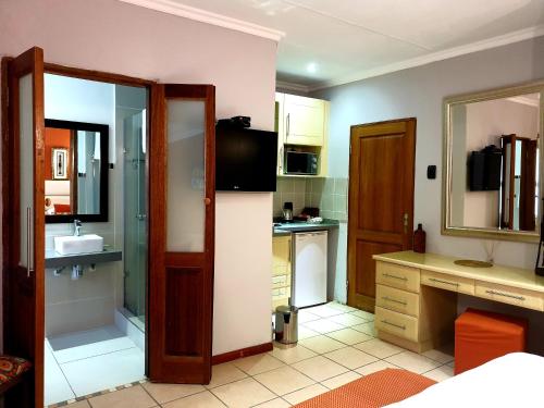 a small kitchen with a sink and a mirror at Damicha Boutique Lodge in Ezulwini