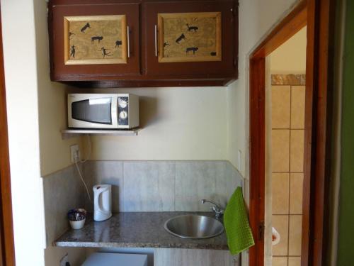 a small kitchen with a sink and a microwave at Lephalale Guest House in Ellisras