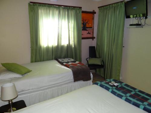 a room with two beds and a window with green curtains at Lephalale Guest House in Ellisras