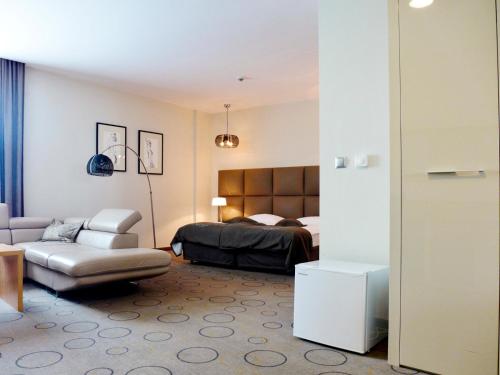 a bedroom with a bed and a couch and a chair at Aroma Stone Hotel Spa in Syców