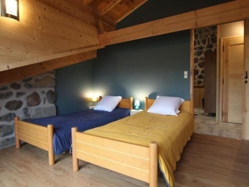 two beds in a room with wooden ceilings at Gîte confortable près de la Cascade de la Beaume avec terrasses et parking privatif - FR-1-582-30 in Solignac-sur-Loire