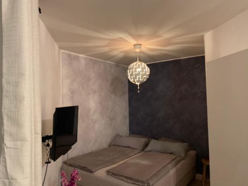 Schlafzimmer mit einem Bett, einem TV und einem Kronleuchter in der Unterkunft Mini-Ferien-Suite Hildesheim in Hildesheim