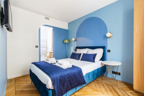 Dormitorio azul con cama y mesa en CMG - Bastille / Charonne, en París