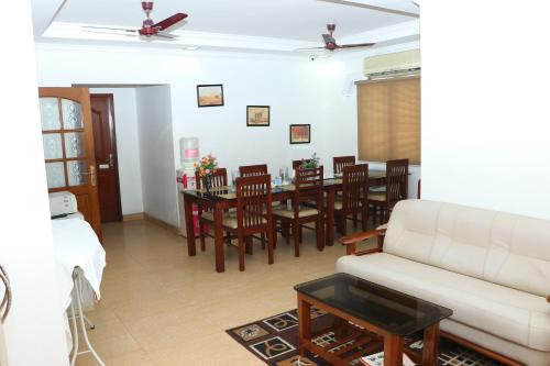 a living room with a couch and a table and chairs at Swarna Sudarshan Service Apartment @ Adyar chennai in Chennai