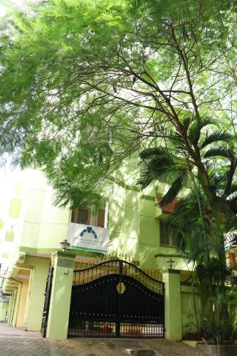 a green building with a tree in front of it at Swarna Sudarshan Service Apartment @ Adyar chennai in Chennai