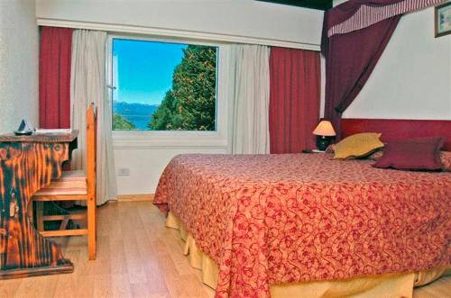 Un dormitorio con una cama y una ventana grande. en Ruca Cheli Village Ski Hotel, en San Carlos de Bariloche