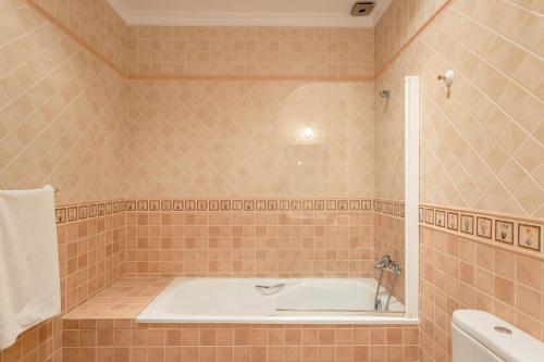 a bath tub in a tiled bathroom with a sink at Casa rural Villena in Frigiliana