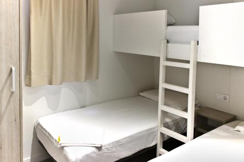 a room with two bunk beds and a ladder at Camping Joncar Mar in Roses