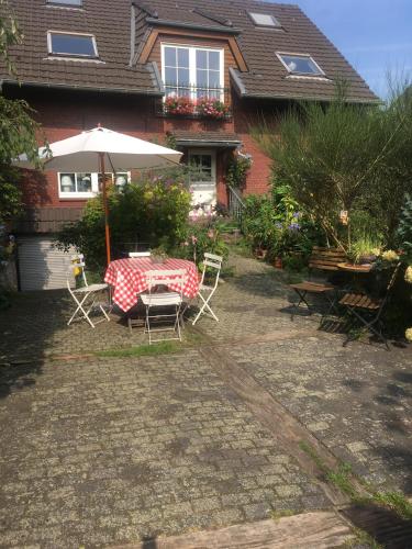 a table and chairs with an umbrella in front of a house at Haus Rothenstein, ruhige FeWo, ca. 10 min. zu Messe und Flughafen in Meerbusch